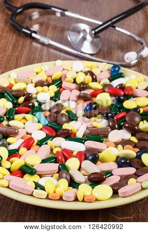 Medical pills capsules or supplements for therapy on plate and stethoscope in background concept of treatment health care