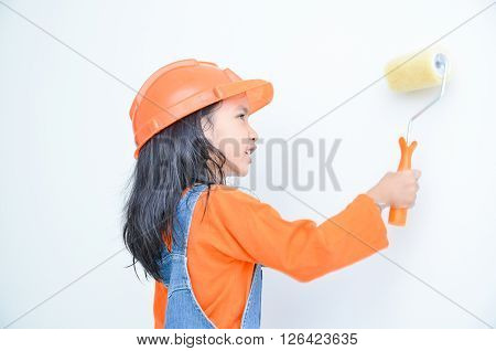 Smile cute asian little girl holding paint roller with copy space in the white room