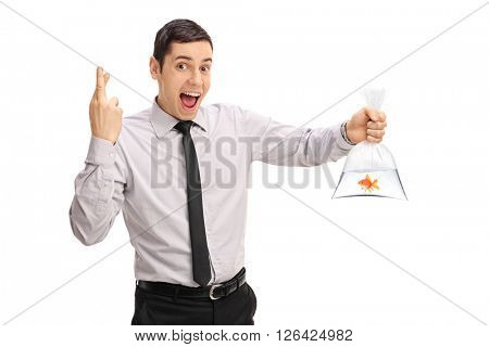 Young man holding a goldfish in a plastic bag and crossing his fingers isolated on white background