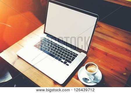 Portable net-book and cup of coffee lying on a table in cafe bar interior open computer with copy space for your text message or promotional content distance work via internet during recreation time