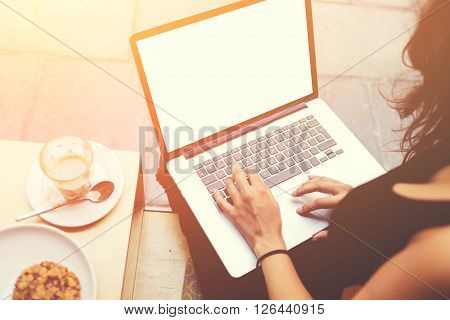 Closeup of woman's hands typing text on laptop computer keyboard during coffee break young female designer is using net-book with mock up blank copy space screen for text message or advertise concept
