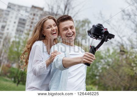 Happy young family taking selfies with her camera on the gimbal steadycam