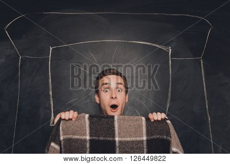 Schocked Young Man Lying With Plaid In Drawn Bed