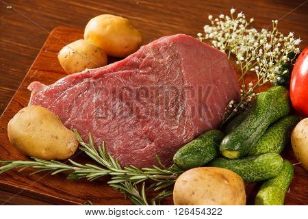 Raw meat with vegetables on a wooden table for a delicious dinner