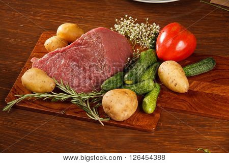 Raw meat with vegetables on a wooden table for a delicious dinner