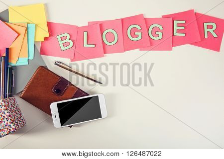Blogger word on a table with  phone and pocketbook.