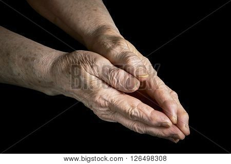 Old woman clasped in her hands on a black background
