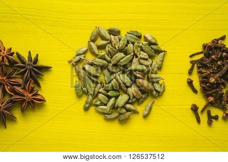 different spices - anise stars cardamon clove nutmeg on a yellow background