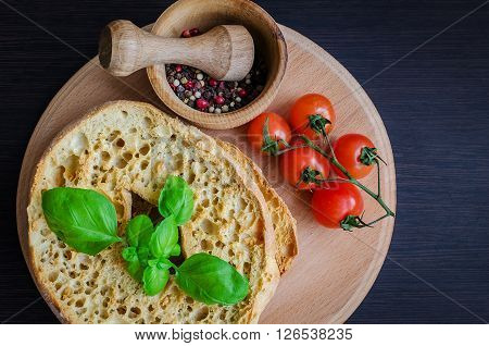 Italian dried bread Friselle on wooden board with tomatoes cherry, basil and peppercorns in wooden pounder. Italian food. Healthy vegetarian food.