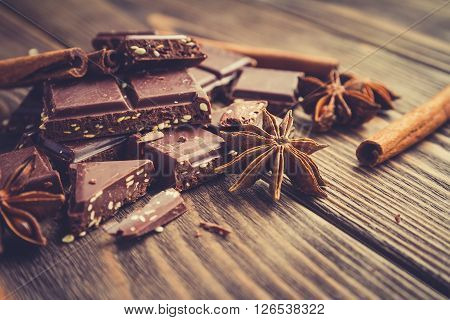 Chocolate bar and spices on wooden table. Selective focus vintage toning