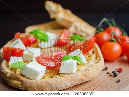 Italian starter friselle. Classical frisella tomato, cheese mozzarella and basil with oregano and olive oil. Dried bread called freselle on wooden board. Italian food. Healthy vegetarian food.