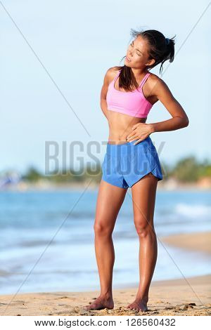Side cramps - woman runner having side stitch after running. Jogging woman with stomach side pain during jogging work out. Female athlete on beach.
