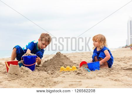 little boy and girl play with sand on beach