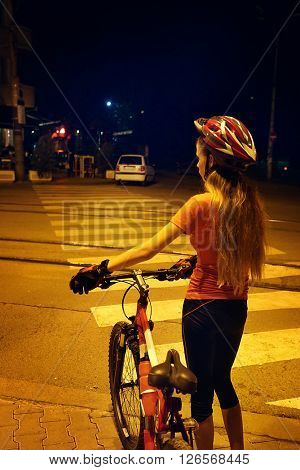 Girl is crossing  zebra crosswalk on bicycle at night city.