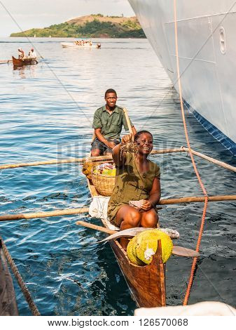 Hell-Ville Madagascar - December 19 2015: Malagasy vendors from their outrigger canoe offer crabs fish and tropical fruits to ship passengers at Hell-Ville Nosy Be Island Madagascar.