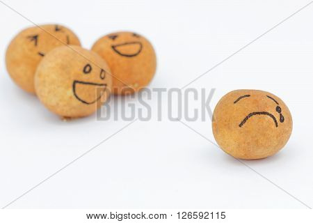 A group of brown ball laughing in the background while the brown ball in front alone and look sad and depressed. Concept of discrimination,bully,mental illness.