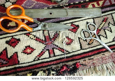 Worn old woolen carpet with scissors,a comb with needle and thread