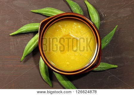 Overhead view of a bowl of Indian Arhar daal lentils and okra with a dollop of desi ghee or clarified butter.
