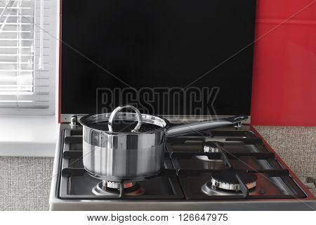stainless pan with handle and cover on a gas stove in the kitchen