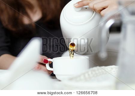 side view of a girls pouring tea, pouring tea from teapot into a cup close-up