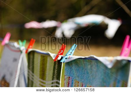 Clothespins holding laundry on the drying line drying clothes outside on fresh air wind and sun. Housework family life household natural living and lifestyle concept.