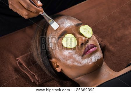 Woman Applying Facial Mask In Spa