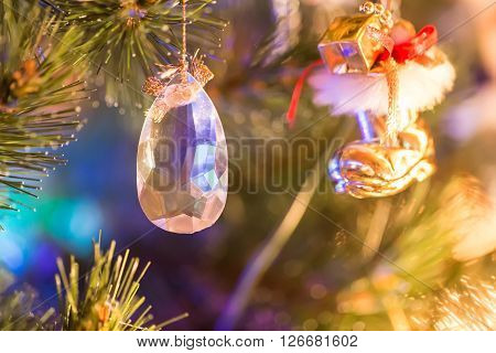 Jewel toy hanging on christmas tree with reflectiions and lights
