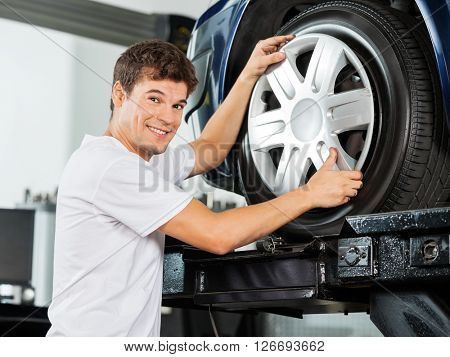 Happy Mechanic Fixing Hubcap To Car Tire