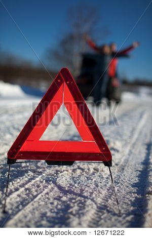 Mand og kvinde brudt ned på landevej med Hazard advarselsskilt i forgrunden
