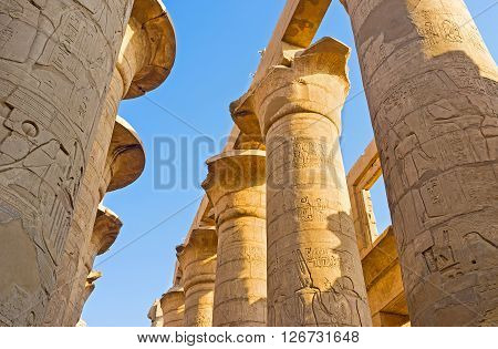 LUXOR EGYPT - OCTOBER 7 2014: The rows of the massive stone columns covered with the reliefs with ancient hieroglyphs pharaohs and gods in the Hypostyle Hall of Karnak Temple  on October 7 in Luxor.