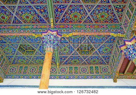KOKAND UZBEKISTAN - MAY 6 2015: The ceiling of the Iwan in Jami Mosque covered with the islamic patterns and supported by the wooden pillars with the carved colorful capitals on May 6 in Kokand.