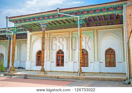 KOKAND UZBEKISTAN - MAY 6 2015: The courtyard of Khudayar Khan Palace with the shady arcades decorated ceilings carved wooden pillars and ornaments on the plaster walls on May 6 in Kokand.