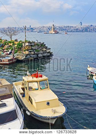 ISTANBUL TURKEY - JANUARY 21 2015: The small fishing boats in harbor and the medieval lighthouse on the background on January 21 in Istanbul.