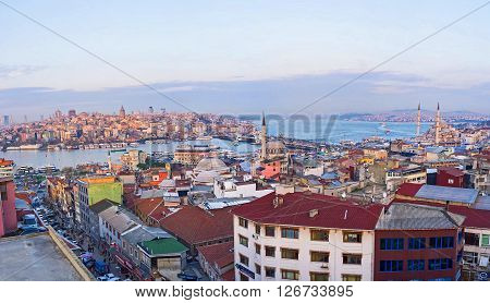 The old roofs of the Fatih district with the blue waters of Golden Horn Bay and Beyoglu district in the sunset rays on the background Istanbul Turkey.