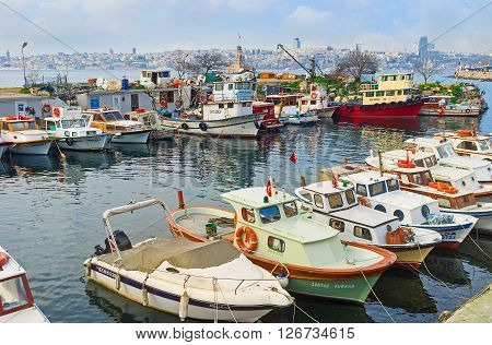 ISTANBUL TURKEY - JANUARY 21 2015: The old fishing boats in harbor in Uskudar district with the Maiden's Tower on the background on January 21 in Istanbul.