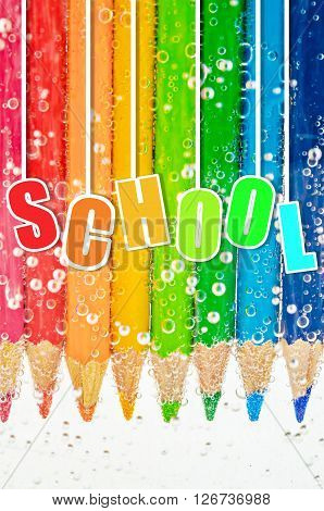 School. Close up colorful wooden pencils in sada water with bubbles