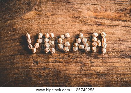 vegan written with chickpeas on wood background
