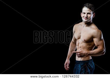 Studio shot on black background. Showing six packs of abs.