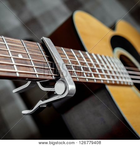 Acoustic guitar neck with a capo, selecive focus