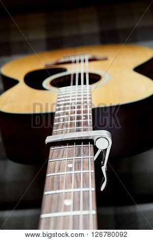 Acoustic guitar neck with a capo, selecive focus