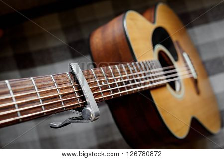 Acoustic guitar neck with a capo, selecive focus