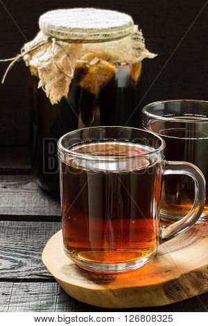 Traditional Russian drink kvass made from bread rye malt sugar and water. Kvass in the jug and mug on a dark wooden background. Selective focus