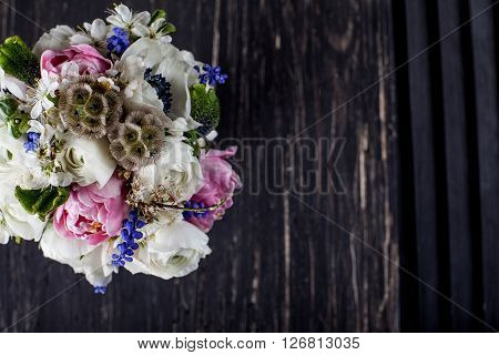 Bouquet from pink tulips violet grape hyacinths white anemones violet veronica and white buttercup with violet ribbon on black old wood and shutter from the top