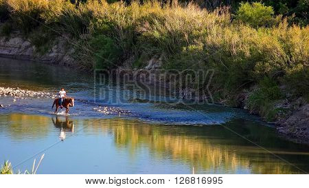BIG BEND NATIONAL PARK, TEXAS - APRIL 3: Mexican national on horseback rides through the Rio Grande River at Big Bend National Park on April 4th, 2016.