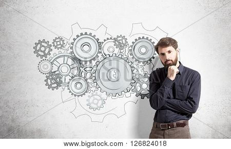 Teamwork concept with businessman standing next to concrete wall with gears skecth