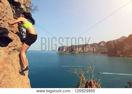 young woman rock climber climbing at seaside mountain rock