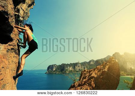 young woman rock climber climbing at seaside mountain rock