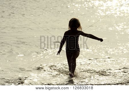Children playing in sunlit sea in summer