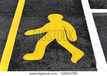 Yellow painted walk sign on tarmac road