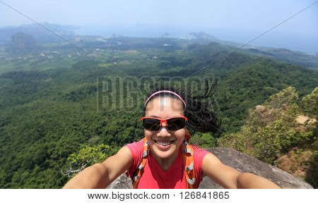 young woman hiker use smartphone taking self photo on seaside mountain top